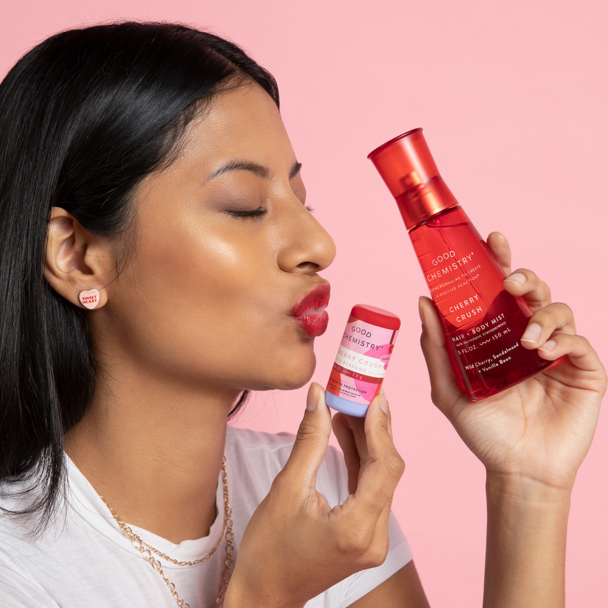 Woman holding Cherry Crush Solid and red body mist with a pink background