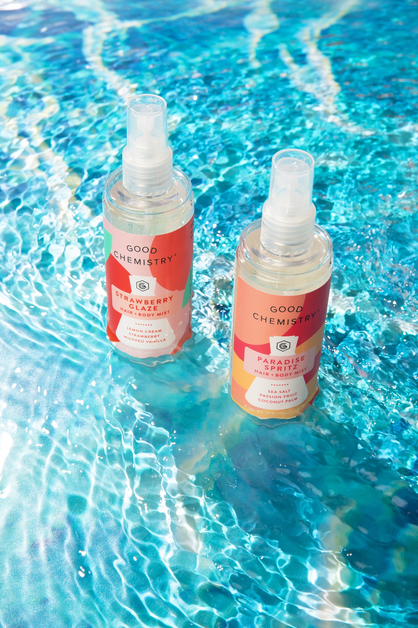 Two bottles of Good Chemistry, Strawberry Glaze and Paradise Spritz, on a pool surface