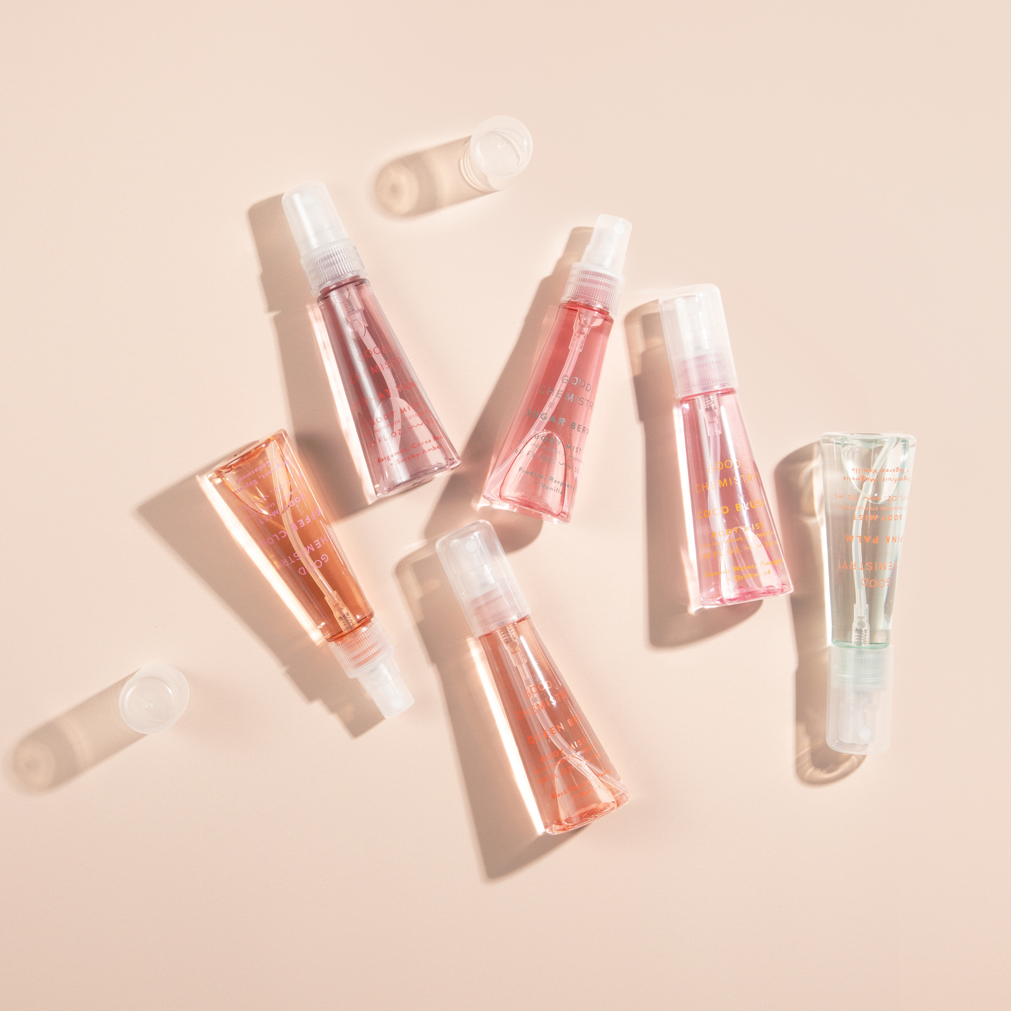 Set of 'good chemistry'  mini body mist bottles with pinkish liquid on a beige background