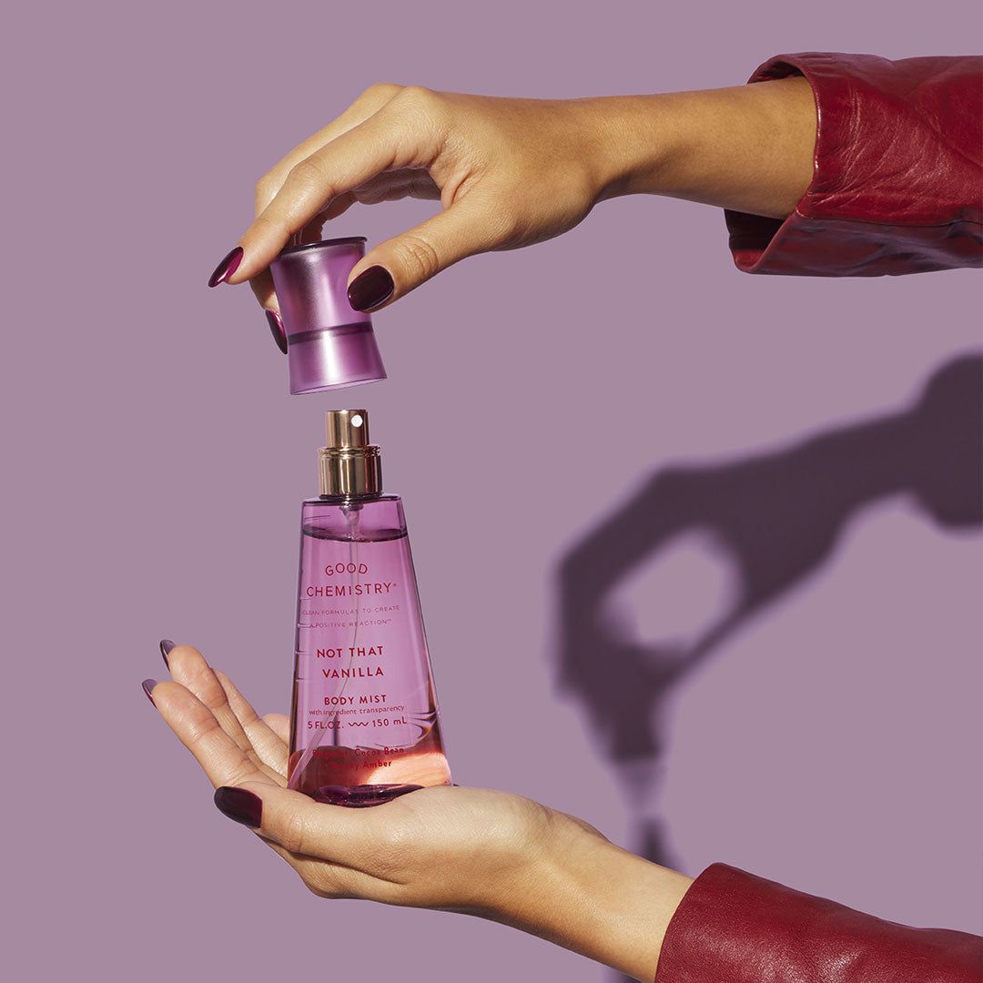 Two hands holding a purple bottle of 'Good Chemistry Not That Vanilla' Body Mist