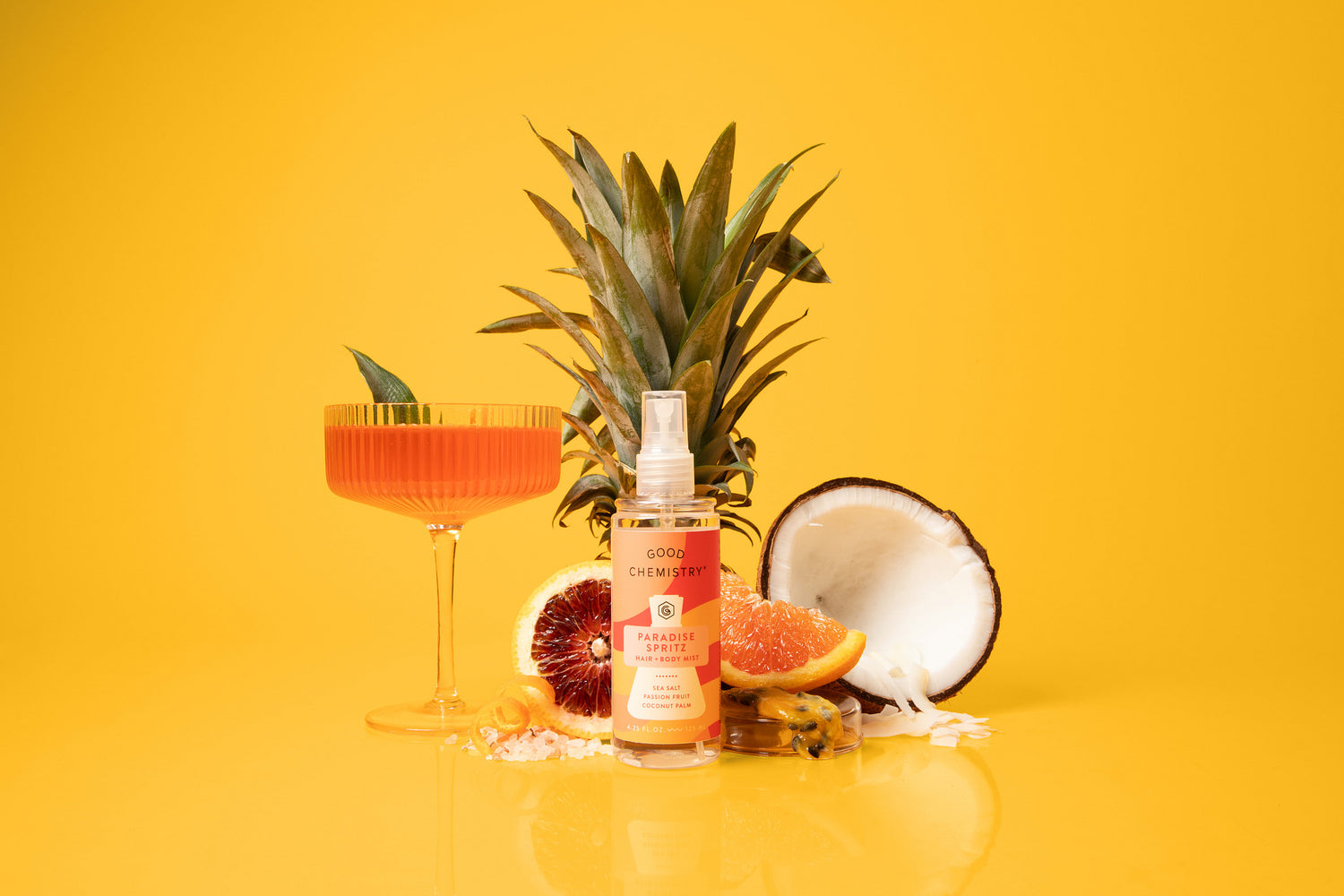 Paradise spritz flavor queues. A cocktail glass with orange drink, pineapple, coconut, and blood orange on a yellow background
