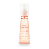 A pink spray bottle labeled 'GOOD CHEMISTRY Queen Bee Body Mist' with text indicating fragrance notes of black currant, peony, and amber.