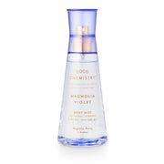 A clear spray bottle labeled 'GOOD CHEMISTRY MAGNOLIA VIOLET BODY MIST' with a blue cap and floral design elements.