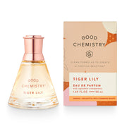 A product image featuring a triangular, clear perfume bottle with a rose gold cap, alongside its packaging. The packaging has a beige background with 'GOOD CHEMISTRY' written at the top and 'TIGER LILY EAU DE PARFUM' at the bottom.